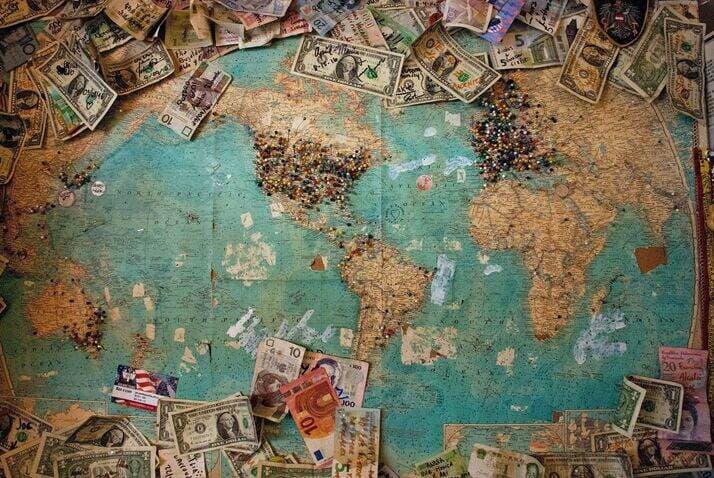 World map covered in pins and money.